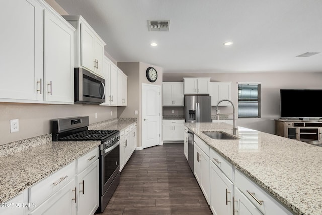 kitchen with a sink, visible vents, white cabinets, appliances with stainless steel finishes, and dark wood-style floors