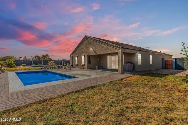 pool at dusk with a fenced in pool, a lawn, a fenced backyard, ceiling fan, and a patio area