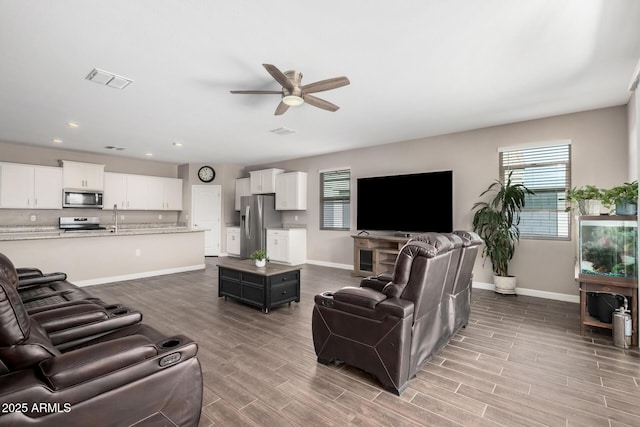 living area featuring visible vents, wood finish floors, a wealth of natural light, and baseboards