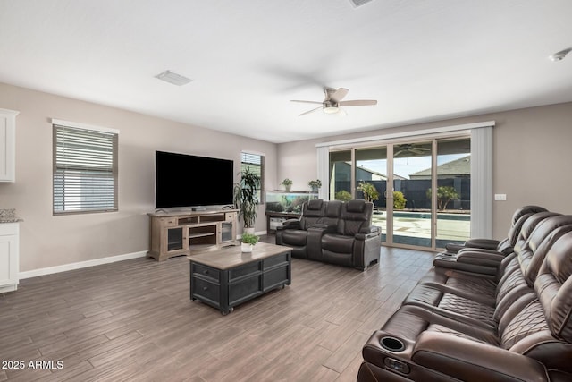 living room featuring visible vents, wood finished floors, a ceiling fan, and baseboards