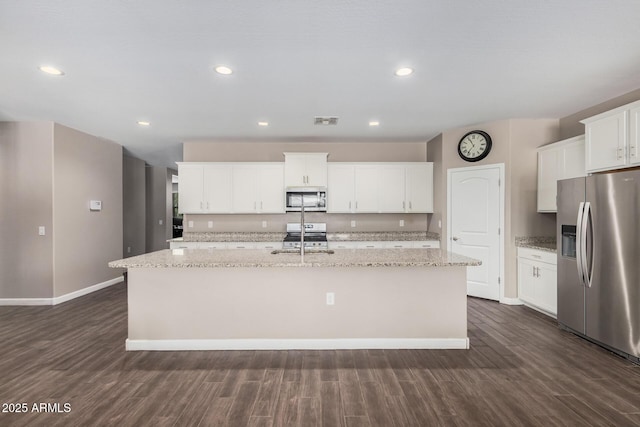 kitchen with stainless steel appliances, visible vents, dark wood-type flooring, white cabinets, and an island with sink