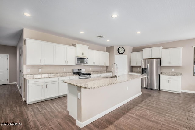 kitchen featuring visible vents, white cabinets, appliances with stainless steel finishes, wood finished floors, and a sink