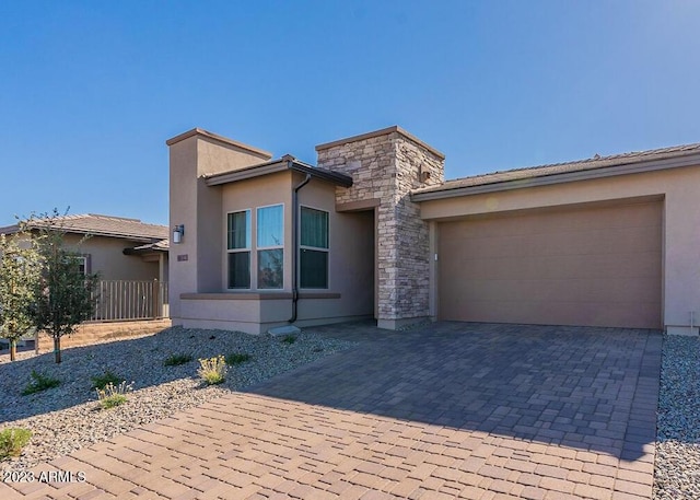 view of front facade featuring stone siding, decorative driveway, an attached garage, and stucco siding