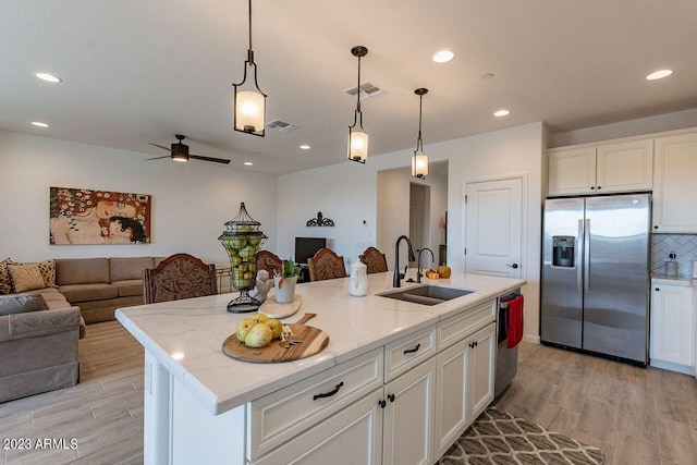 kitchen with appliances with stainless steel finishes, sink, an island with sink, and white cabinets