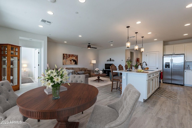 dining space featuring sink, ceiling fan, and light wood-type flooring