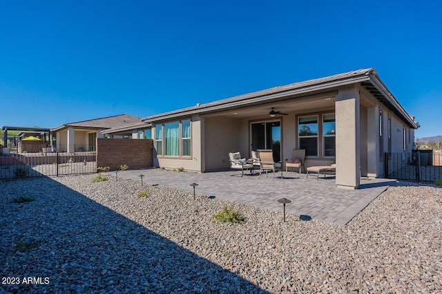 rear view of property with a patio area, fence, a ceiling fan, and stucco siding