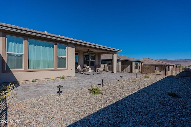 rear view of house with a patio area, fence, and stucco siding