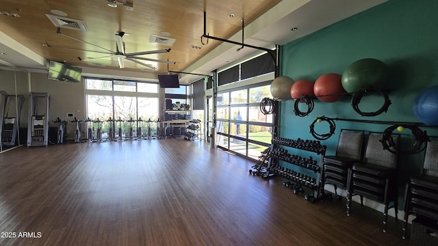 exercise room with a towering ceiling, wood finished floors, and visible vents