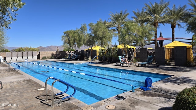 community pool featuring a patio area, fence, and a mountain view