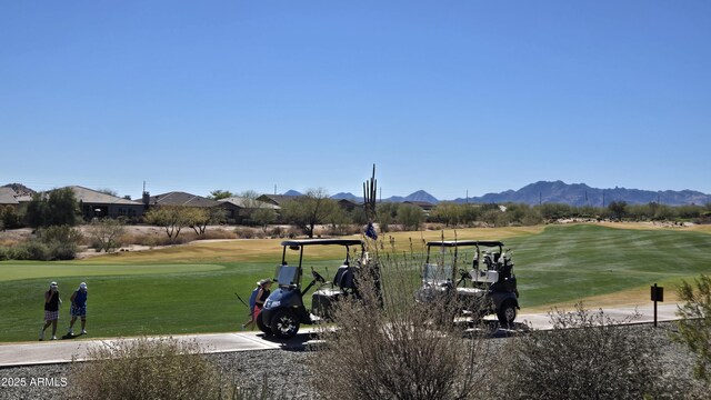 view of community featuring a lawn, golf course view, and a mountain view