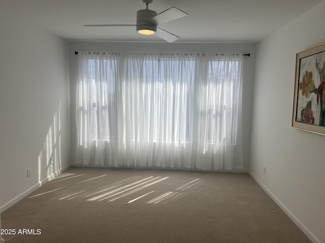 empty room with carpet, a ceiling fan, and baseboards