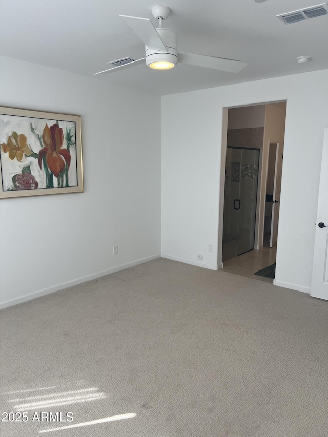 carpeted spare room featuring ceiling fan, visible vents, and baseboards