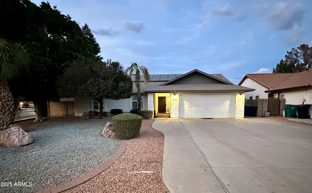 ranch-style home featuring a garage and solar panels