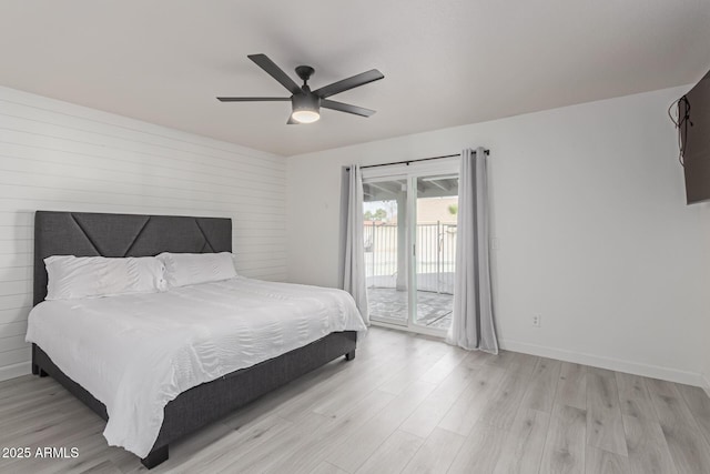 bedroom with access to outside, wood walls, ceiling fan, and light hardwood / wood-style flooring