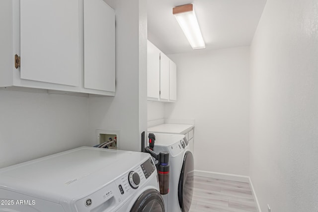 laundry room featuring cabinets, washer and dryer, and light wood-type flooring