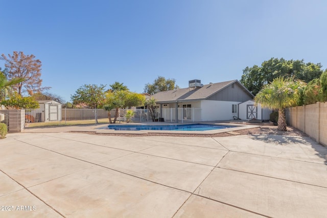 view of swimming pool featuring a patio, central AC unit, and a storage unit