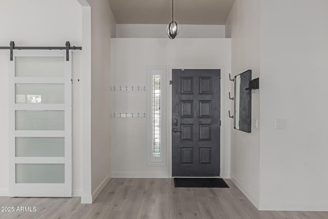 entryway with a barn door and light hardwood / wood-style flooring