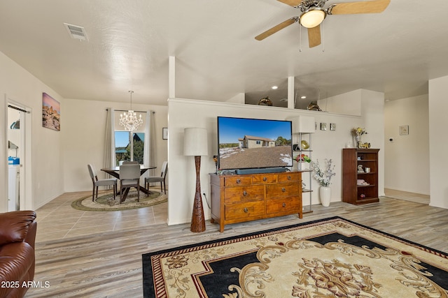 living area featuring visible vents, wood finished floors, and ceiling fan with notable chandelier