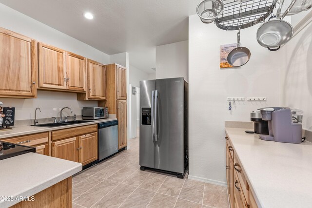 kitchen featuring a sink, stainless steel appliances, a toaster, light tile patterned floors, and light countertops