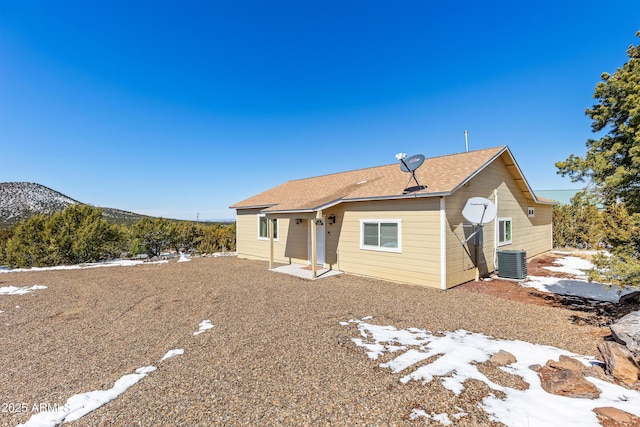 back of property featuring a mountain view, cooling unit, and a shingled roof