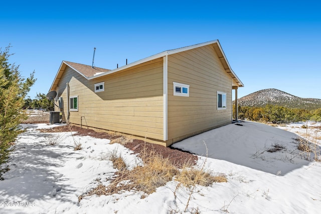 view of snow covered exterior with central air condition unit and a mountain view