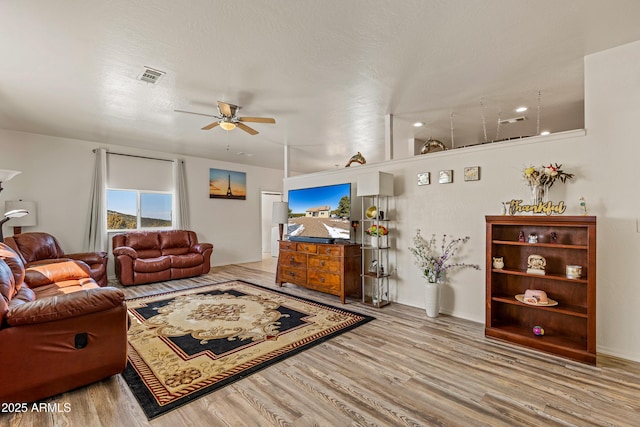 living room featuring visible vents, a ceiling fan, and wood finished floors