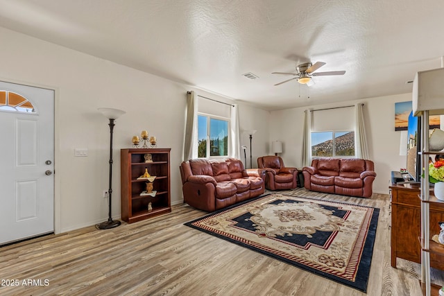 living room featuring visible vents, a textured ceiling, wood finished floors, and a ceiling fan