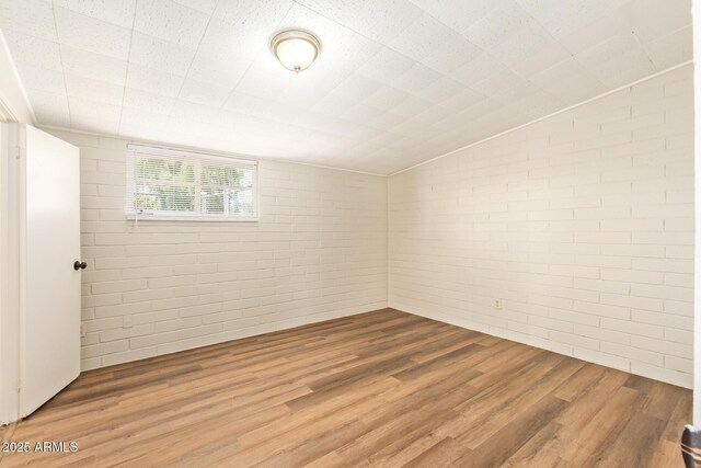 122 N 5th St, Avondale, AZ 85323 - empty room featuring wood finished floors, brick wall, and vaulted ceiling