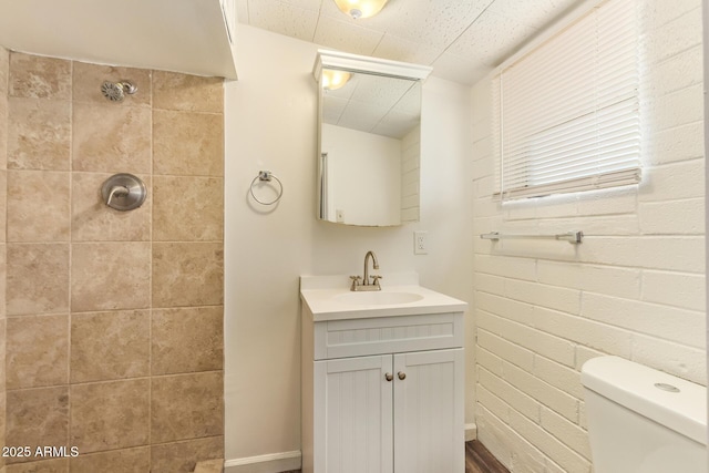 122 N 5th St, Avondale, AZ 85323 - full bathroom featuring vanity, a tile shower, toilet, baseboards, and brick wall