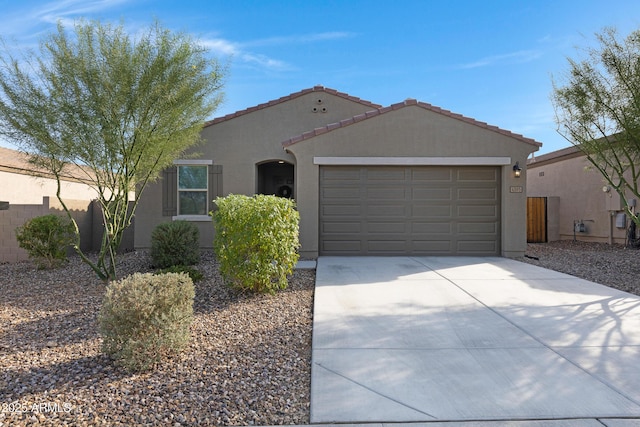 view of front of house featuring concrete driveway, an attached garage, a tiled roof, and stucco siding