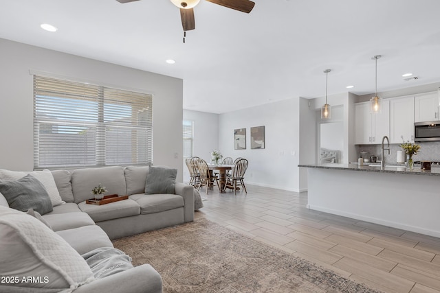 living area featuring ceiling fan, light wood-style flooring, recessed lighting, visible vents, and baseboards