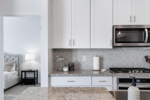 kitchen featuring stainless steel appliances, tasteful backsplash, white cabinetry, and light stone countertops