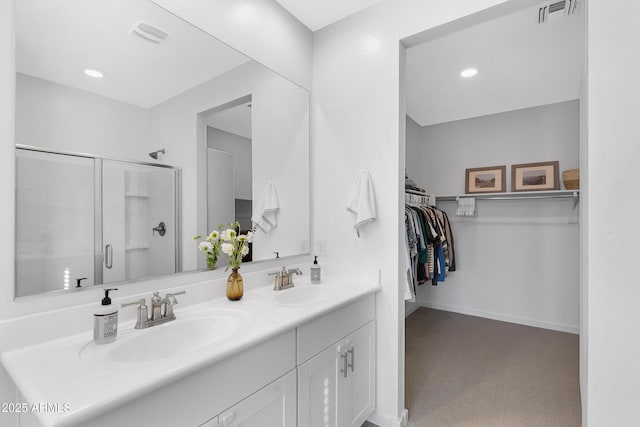 bathroom featuring a stall shower, a sink, visible vents, and a walk in closet