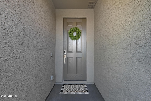 doorway to property featuring visible vents and stucco siding