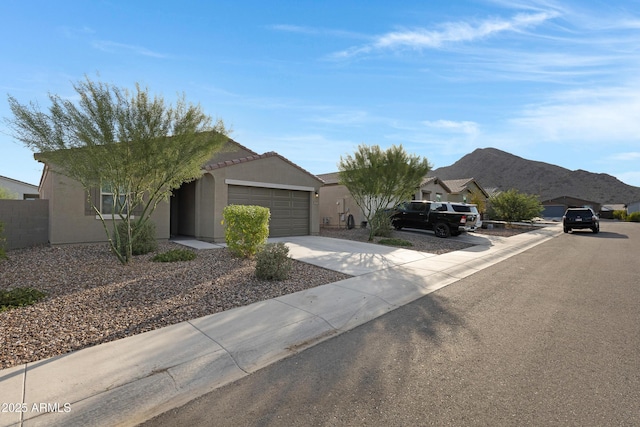 view of front facade with driveway, a garage, a tiled roof, a mountain view, and stucco siding