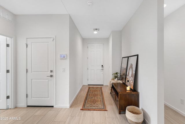 foyer entrance with light wood-type flooring, visible vents, and baseboards