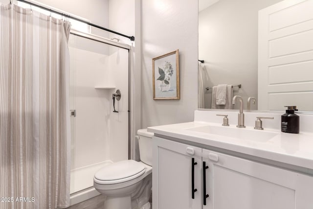 bathroom with a stall shower, vanity, and toilet