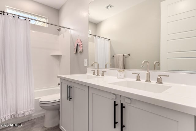 bathroom featuring toilet, shower / bathtub combination with curtain, double vanity, and a sink