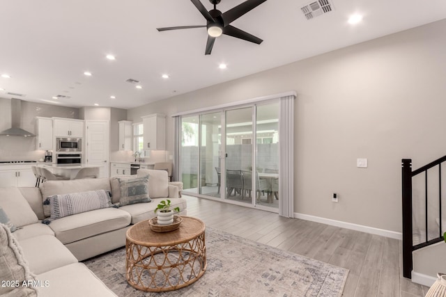 living room with light wood-type flooring, stairs, visible vents, and recessed lighting