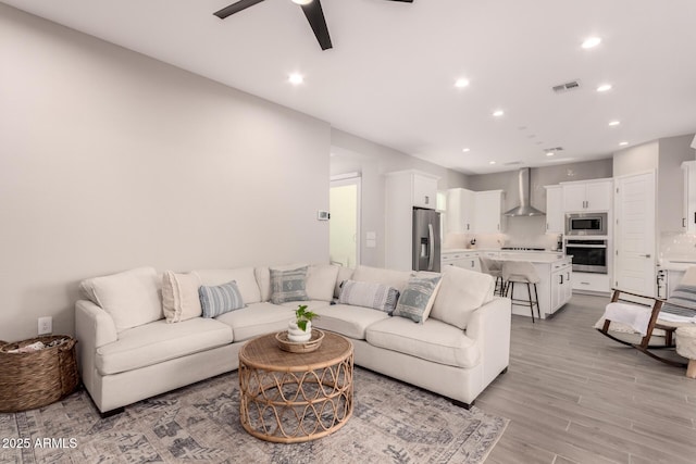 living room with ceiling fan, recessed lighting, visible vents, and light wood-style floors