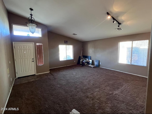 foyer entrance with rail lighting, lofted ceiling, and dark carpet