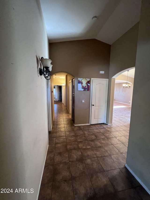 corridor with dark tile patterned flooring and high vaulted ceiling