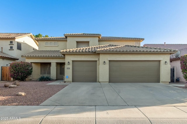 mediterranean / spanish house with a garage, driveway, a tiled roof, and stucco siding