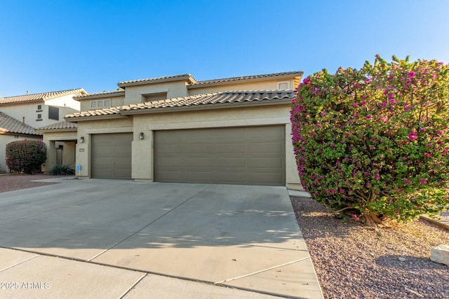 view of front of property featuring an attached garage, a tile roof, concrete driveway, and stucco siding