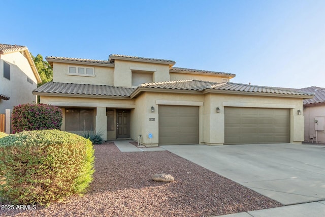 mediterranean / spanish house featuring an attached garage, driveway, a tiled roof, and stucco siding