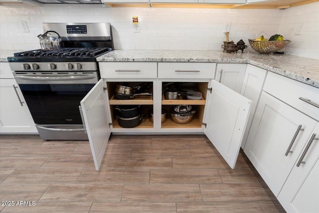 kitchen featuring light stone counters, stainless steel range with gas stovetop, and white cabinets