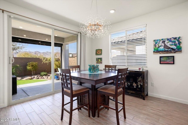 dining area featuring a mountain view, a healthy amount of sunlight, an inviting chandelier, and light hardwood / wood-style floors