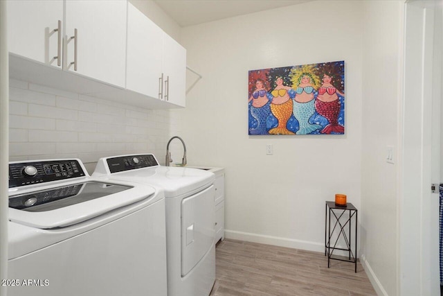 laundry area with cabinets, light wood-type flooring, sink, and washer and clothes dryer