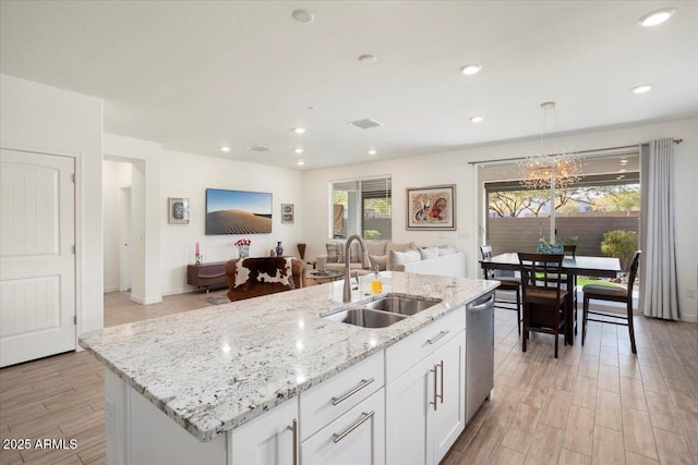 kitchen featuring white cabinetry, sink, light wood-type flooring, and a center island with sink