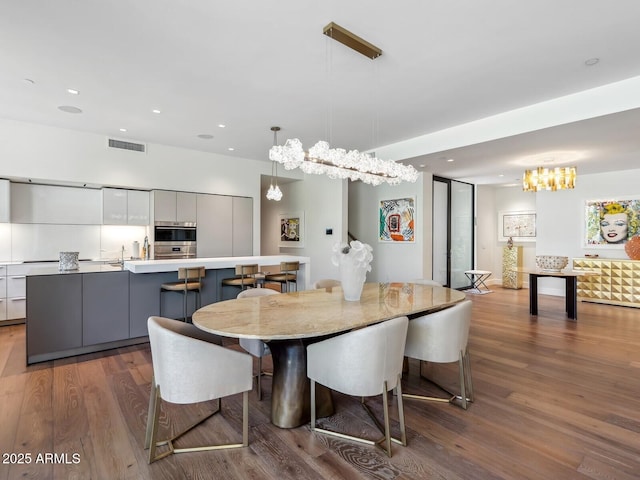 dining space with wood finished floors, a chandelier, and recessed lighting